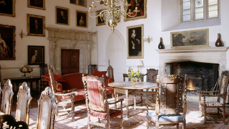A view of the Great Hall at Clevedon Court looking north-west. The stone fireplace has a picture and window above. There is a C17th Dutch chandelier and a drawer table.The chairs are Stuart.
